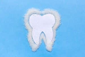 White tooth shape surrounded by fluffy clouds on blue background, dental care concept