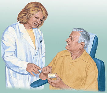 Dentist showing dental implant prosthesis model to male patient during consultation.