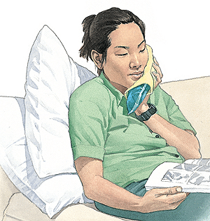 Woman in green shirt holding dental x-rays while sitting in dental chair.
