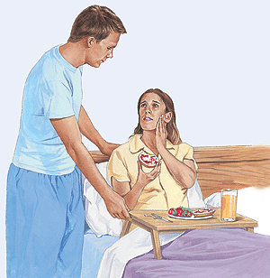 Man placing hand on woman's shoulder while she holds her jaw in pain, illustrating TMD symptoms.