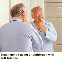 Older man brushing teeth gently with soft-bristled toothbrush for sensitive teeth care.