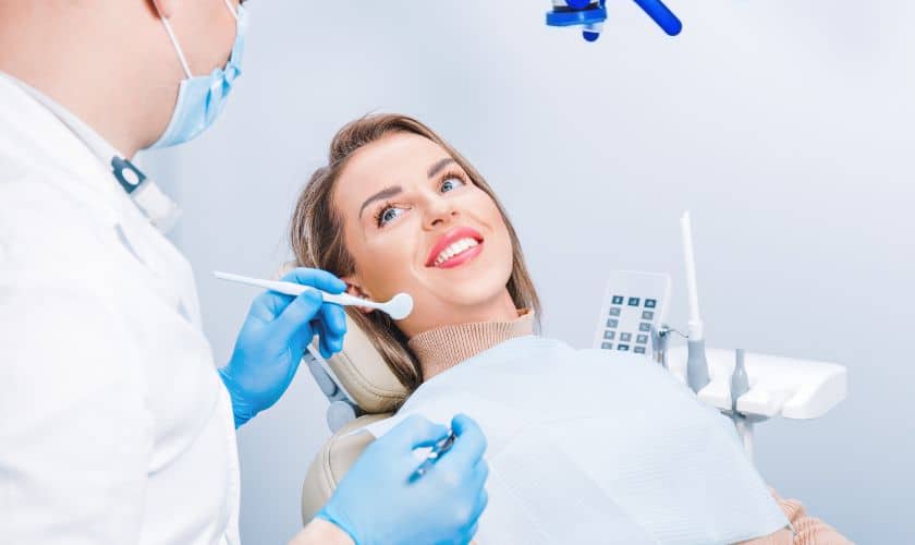Dentist in blue gloves examining patient's teeth during dental checkup in clinical setting.