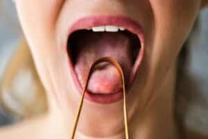 Person with open mouth demonstrating oral health or dental examination technique, close-up view.
