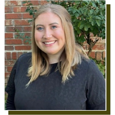 Professional headshot of smiling woman against brick wall with ivy at dental practice.